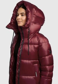 Burgundy padded jacket with a large hood, zippers, and black drawstrings. Smooth, shiny texture with horizontal quilted pattern and side pockets.