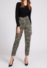 Pantalons cargo à imprimé camouflage dans des nuances de vert et de marron, avec une taille haute, des passants de ceinture, des poches avant et une coupe fuselée.