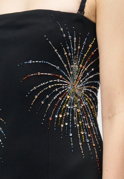 Fekete ruha, mely részletes gyöngyfűzéssel díszített, robbanásmintázatban, színes gyöngyökkel kék, arany, narancs és ezüst �árnyalatokban a szöveten.