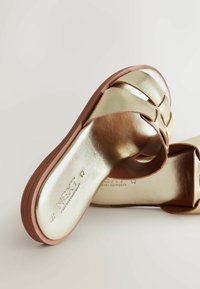 Guld metallic slide sandaler med en glat overflade, åben design og en brun gummisål. Har "NEXT" branding på indersålen.