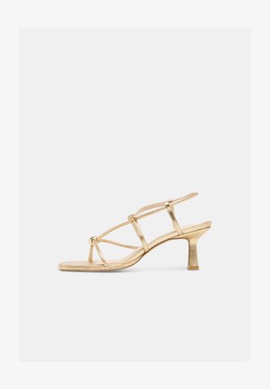 Gylden sandal med tynde stropper, lav blokhæl og ankelrem, med tynde metalliske stropper og åben tå.