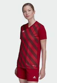 Rotes Sporttrikot mit V-Ausschnitt, kurzen Ärmeln und diagonalen Streifen in dunklerem Rot. Verfügt über das adidas-Logo auf der linken Brust und am Arm.