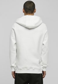 Weißer Hoodie mit einer weichen, glatten Textur, ausgestattet mit einer großen Kapuze, gerippten Bündchen und einem geraden Saum. Maßgeschneiderte Passform von hinten gezeigt.