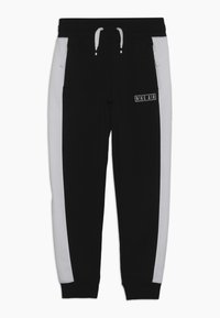 Svarta sweatpants med vita sidostripe, utrustade med ett elastiskt midjeband, dragsko och en "Nike Air"-logotyp på framsidan.
