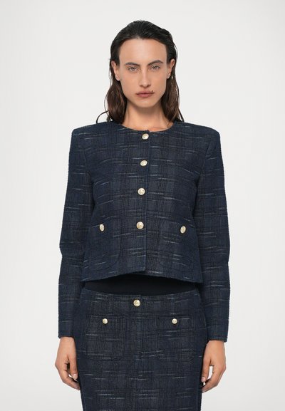 Marineblå tweedjakke med cropped design, guldknaplukninger, to forlommer og et struktureret vævet mønster.