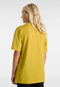 Gul bomullströja med korta ärmar, avslappnad passform och rund hals. Har rena sömmar och inga synliga logotyper eller mönster.