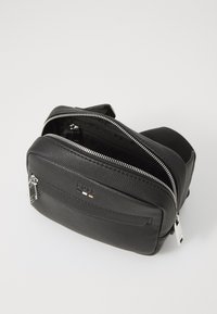 Schwarze Lederhandtasche mit strukturiertem Finish, doppelten Reißverschlüssen und silbernem Zubehör. Verfügt über eine Vorderseitentasche und ein geräumiges Hauptfach.