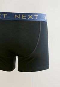 Boxer noir pour homme avec une ceinture élastique bleue portant le nom de la marque « NEXT » en lettres dorées.