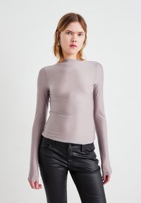 Duga majica s dugim rukavima u svijetlosivoj boji, izrađena od glatkog materijala s prilagođenim krojem, s visokim izrezom i suptilnim detaljima šavova.