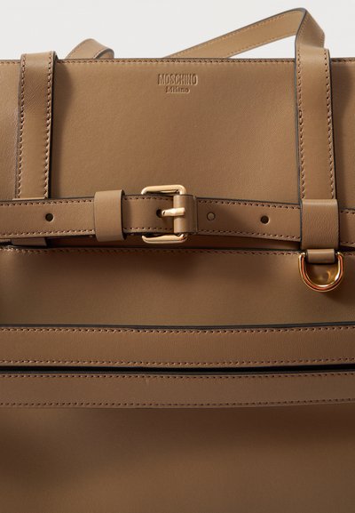 Sac cabas Moschino Milano en cuir marron avec détail cousu, bandoulière réglable, boucle et anneau en métal doré.