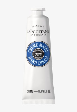 Tubka kremu do rąk L'Occitane z 20% masła shea, niebieska okrągła etykieta, pojemność 30 ml (1 oz), białe opakowanie z czarnym tekstem.