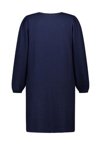 Marineblauwe gebreide jurk met lange pofmouwen, ronde halslijn en gestructureerde stof. De zoom valt halverwege de dij. Eenvoudig, klassiek ontwerp.