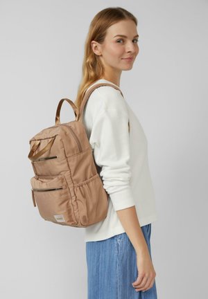 Zaino in nylon marrone con diverse tasche con cerniera e una tasca laterale con coulisse. Texture morbida e forma rettangolare con spalline regolabili.