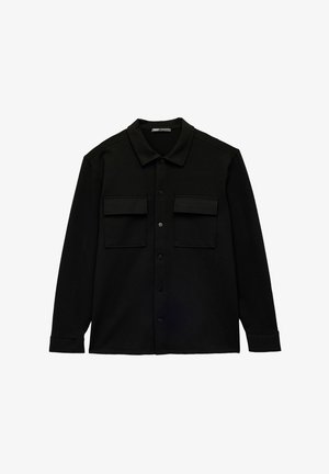 Chemise noire à manches longues en tissu doux avec un col pointu, dotée de deux poches poitrine et d'une finition droite. Pas de motifs ni d'accents visibles.