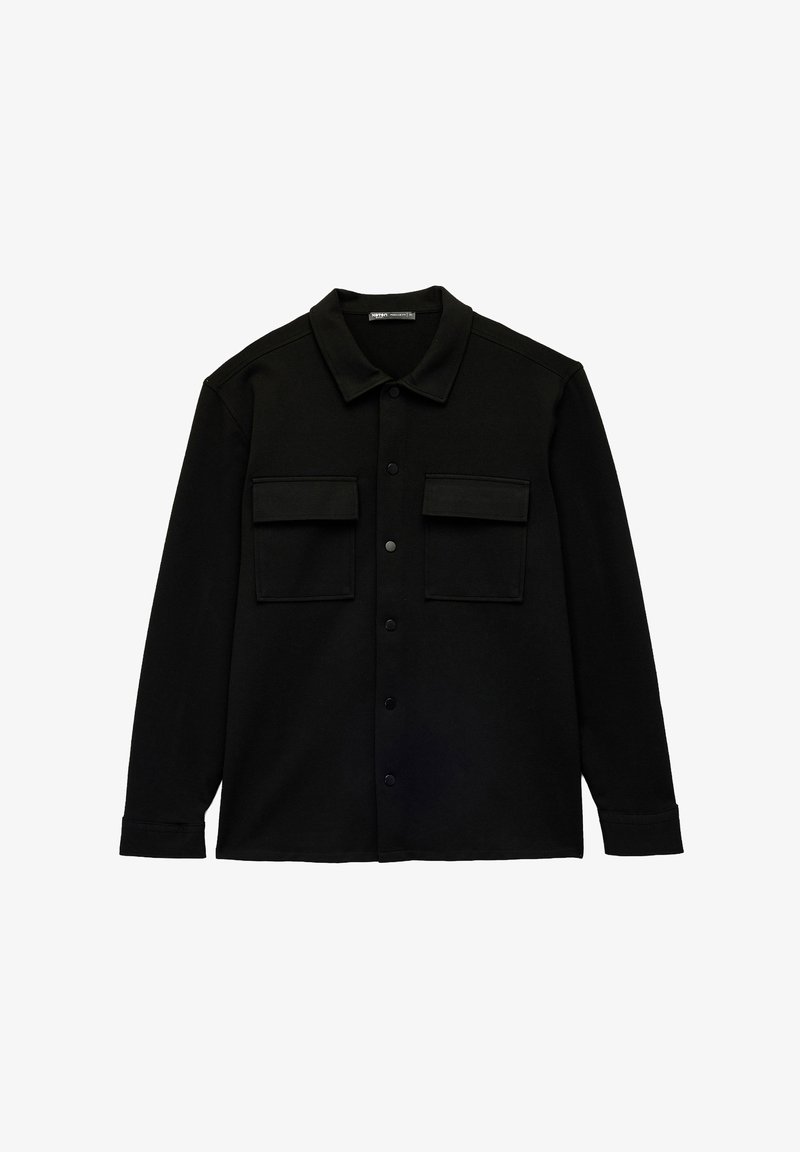 Camicia nera con bottoni, realizzata in tessuto morbido, con colletto a punta, due tasche sul petto e orlo dritto. Senza motivi o accenti visibili.