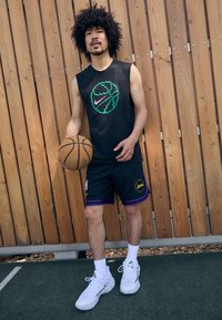 Čierny bezrukávový dres s grafickým motívom basketbalu v zeleno-ružových farbách, kombinovaný s čiernymi šortkami so fialovými akcentmi a logom Lakers; biele tenisky.