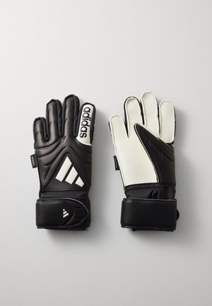 Melnas un baltas vārtsargu cimdus ar polsterētām pirkstiem, teksturētu saķeri, regulējamu plaukstas siksnu un Adidas zīmolu uz aizmugurējās daļas.