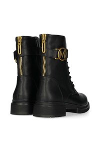 Botas de tobillo de cuero negro con detalles en dorado, incluyendo cremalleras y un logotipo circular. Acabado texturizado con una suela de goma gruesa.