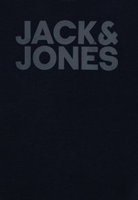 Mörk marinblå bomulls-t-shirt med stora, tydliga grå bokstäver som stavar "JACK & JONES." Enkelt mönster utan ytterligare mönster eller accenter.
