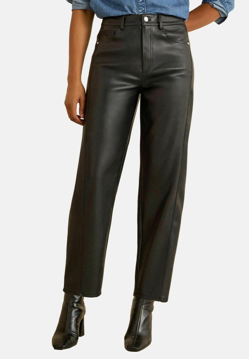 Črne usnjene hlače z visokim pasom in ravnim krojem, opremljene s sprednjimi žepi in kontrastnim šivom, v kombinaciji s črnimi črnimi škornji s peto.