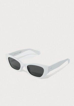 White cat-eye sunglasses with black lenses angled on a light surface, showing slight shadow underneath.