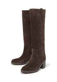 Botas de ante marrón hasta la rodilla con una textura suave, puntera cuadrada y tacón de bloque. Presentan un diseño de costura sutil y una construcción resistente.