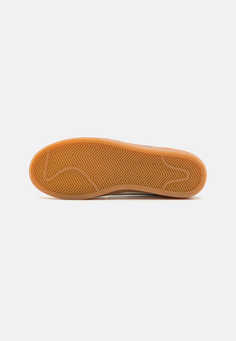Suela de zapato con una superficie de goma texturada en color naranja, que presenta un patrón de espiga para agarre y soporte. Diseño plano y ancho.