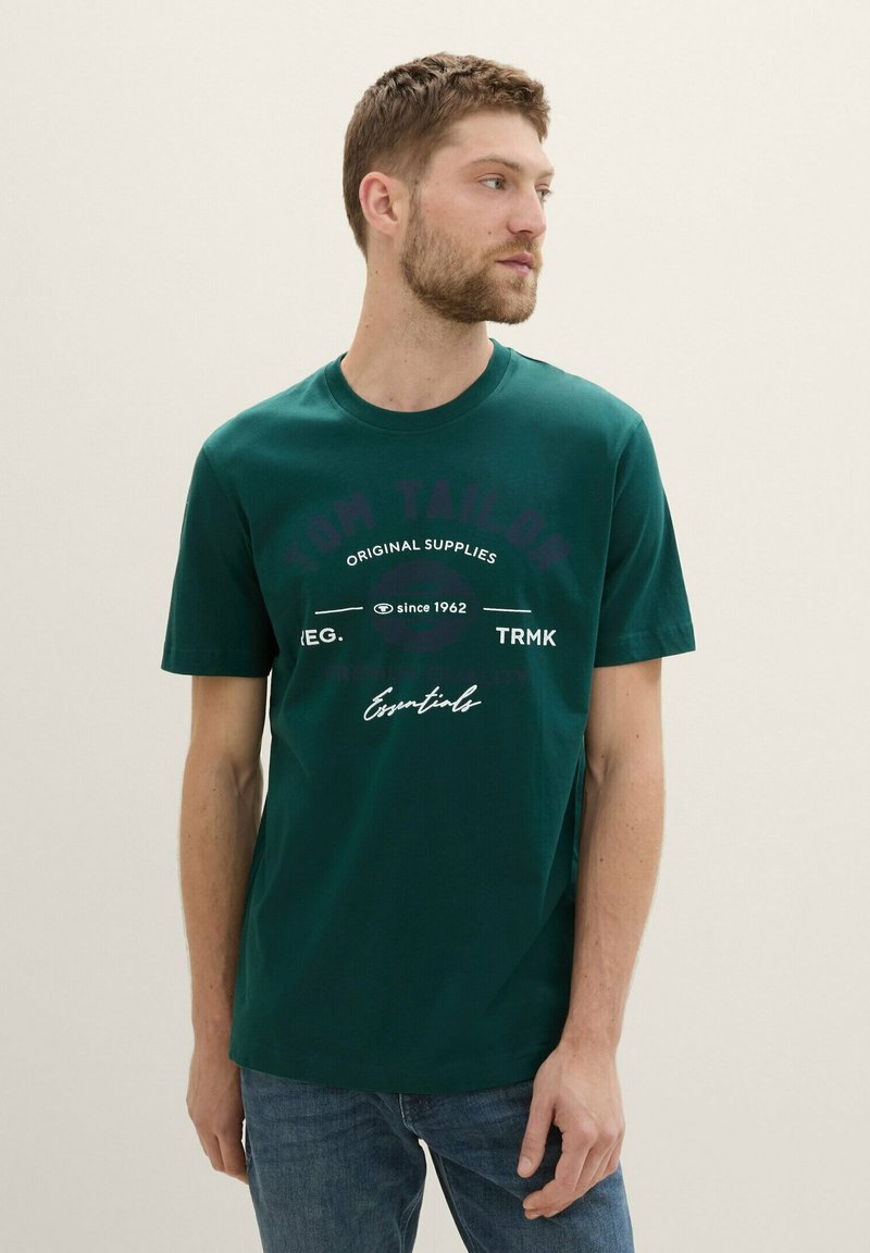 Grøn bomulds t-shirt med rund hals, korte ærmer og grafisk tekstdesign i kontrastfarver på forsiden.