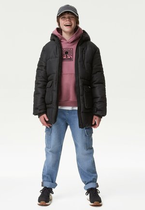 Doudoune noire avec capuche, sweat à capuche rose avec design graphique, jean bleu avec poches cargo, et baskets noires avec semelles marron.