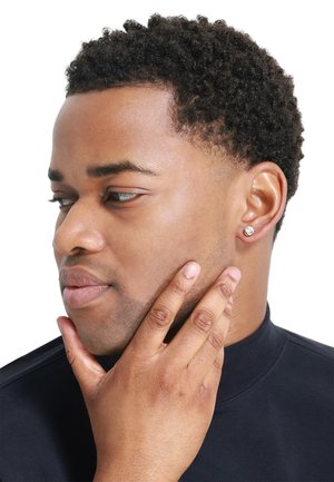 Silver stud earring on a dark-skinned male model. The earring features a round shape with a small gemstone detail. Short, curly hair.
