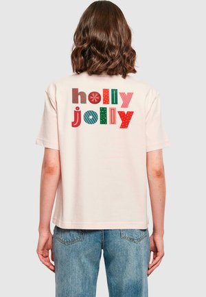 Lys rosa bomull T-skjorte med teksten "holly jolly" i flerfargede, mønstrede bokstaver. Korte ermer og en avslappet passform.