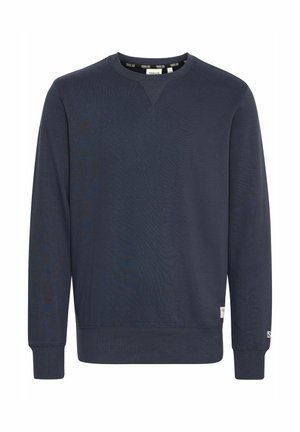 Sudadera azul marino hecha de una tela suave, con cuello redondo, mangas largas, puños acanalados y una pequeña etiqueta de la marca en el dobladillo inferior.