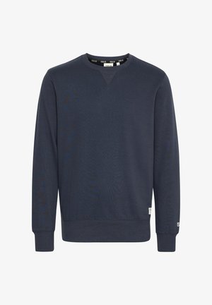 Dziļa zila sporta krekliņa izgatavots no mīksta auduma, ar apaļu izgriezumu, garām piedurknēm, ribotām aprocēm un mazu zīmola birku apakšējā malā.