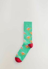 Chaussette en coton verte avec un motif de dinosaures répété en orange et violet, une pointe rouge et un bord côtelé pour plus de texture.