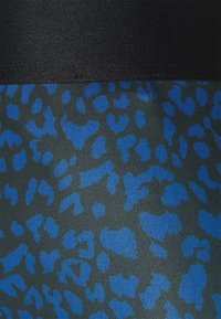 Tissu stretch avec ceinture noire et motif léopard bleu sur fond gris foncé.