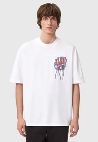 Hvit bomull t-skjorte med rund hals og kortermede, med et fargerikt grafisk design i rødt og blått på fronten.