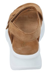 Braune Wildledersandale mit zwei verstellbaren Riemen, weichem Innenfutter und einer weißen Plateausohle, die eine strukturierte Außensohle für besseren Halt aufweist.