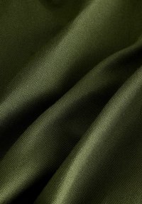 Tamnozelena tkanina s teksturiranim tkanjem, koja prikazuje meke nabore i glatku draperiju. Materijal izgleda lagano i svestrano za razne upotrebe.