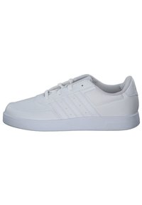 Baskets blanches en cuir synthétique avec une semelle en caoutchouc. Elles présentent trois bandes horizontales et un laçage à l'avant. Texture lisse.