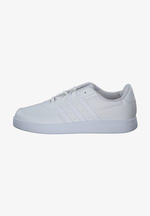 Zapatilla deportiva blanca hecha de cuero sintético con suela de goma. Presenta tres franjas horizontales y un cierre de cordones en la parte frontal. Textura suave.