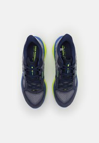 Paire de chaussures de course Nike bleu marine et grises avec des accents et des lacets vert néon sur un fond blanc, vue de dessus.