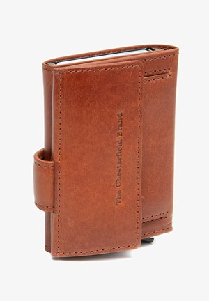 Billetera de cuero marrón, con una textura suave, bordes cosidos y un logo en relieve. Diseño compacto con un anillo lateral para mayor funcionalidad.