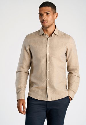 Lichtbeige shirt met lange mouwen van gestructureerde stof, met een knoopsluiting aan de voorkant en een afgeronde zoom, gecombineerd met donkerblauwe broek.