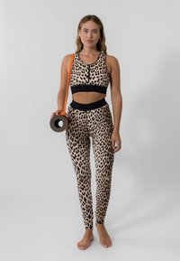 Leopardmønstret activewear-set med sorte detaljer. Sports BH med rund halsudskæring; leggings der sidder tæt med ankelmanchetter. Inkluderer en yogamåtte.