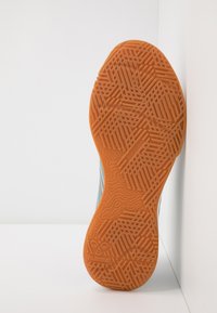 Oranje rubberen zool met een gestructureerd patroon; bevat logo en een niet-markerende ontwerp; gezien vanuit boven tegen een witte achtergrond.