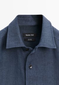 Dunkelblaues Leinenhemd mit geknöpftem Kragen und sichtbarem Markenschild Massimo Dutti, das im Halsausschnitt eingenäht ist.