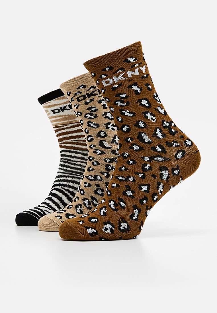 Drie paar sokken: één zwart met strepen, één beige met luipaardprint en één bruin met vlekken. Allemaal hebben ze het DKNY-merk op de boord.