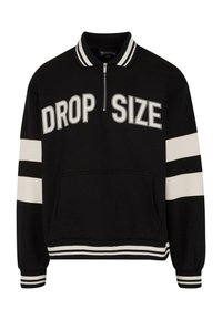 Zwarte rits-pullover met de tekst "DROP SIZE", witte strepen op de mouwen en onderrand, zachte stof en een voorzak. Gestreepte kraagdetails.