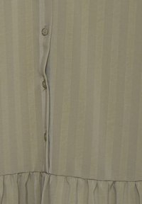 Jasnooliwkowa sukienka z pionowymi paskami, z zapięciem na guziki z przodu i falbaniastym dołem. Gładka faktura z delikatnym połyskiem.