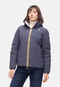 Giacca imbottita grigia con cappuccio, dotata di una cerniera gialla a contrasto, tasche anteriori e un logo discreto sul petto.